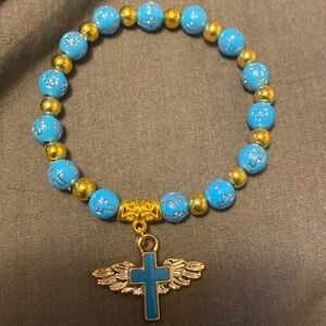 Blue and gold beaded bracelet with a cross with wings pendant